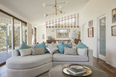 Example of a mid-sized mid-century modern open concept medium tone wood floor and brown floor game room design in Los Angeles with white walls, a standard fireplace, a stone fireplace and a wall-mounted tv