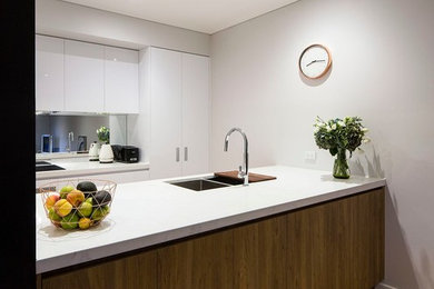 Inspiration for a contemporary kitchen in Melbourne with a double-bowl sink, white cabinets, granite benchtops, multi-coloured splashback, mirror splashback, stainless steel appliances and light hardwood floors.
