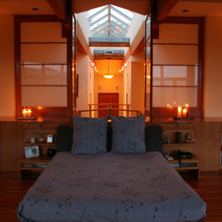 Esempio di una grande camera matrimoniale etnica con pareti beige, pavimento in legno massello medio, camino classico e cornice del camino in intonaco