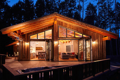 Mid-sized rustic brown one-story wood house exterior idea in Other with a hip roof and a metal roof
