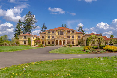 Example of a huge classic yellow two-story stucco house exterior design in Portland