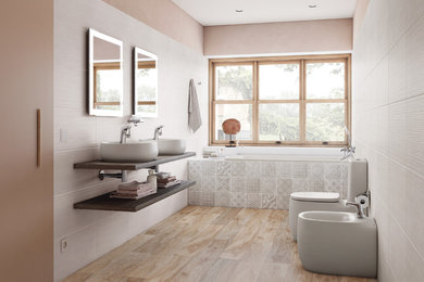 This is an example of a mid-sized contemporary master bathroom in Barcelona with a drop-in tub, a one-piece toilet, beige tile, ceramic tile, beige walls, ceramic floors, a vessel sink, wood benchtops, brown floor and brown benchtops.