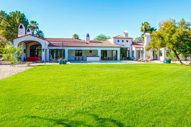 Large tuscan white one-story stucco exterior home photo in Phoenix with a tile roof