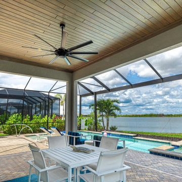 Light natural wood lanai ceiling with a large ceiling fan overlooking the pool a