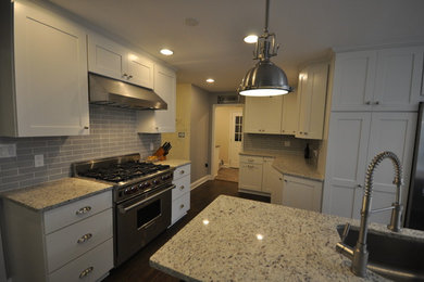 Inspiration for a large transitional u-shaped dark wood floor and brown floor eat-in kitchen remodel in DC Metro with an undermount sink, shaker cabinets, white cabinets, green backsplash, subway tile backsplash, stainless steel appliances and an island