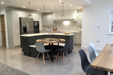 Photo of a mid-sized modern l-shaped open plan kitchen in Kent with an integrated sink, shaker cabinets, grey cabinets, quartzite benchtops, white splashback, stone slab splashback, panelled appliances, porcelain floors, with island, grey floor and white benchtop.