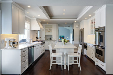 Inspiration for a transitional galley dark wood floor eat-in kitchen remodel in San Francisco with an undermount sink, shaker cabinets, white cabinets, quartz countertops, white backsplash, ceramic backsplash, stainless steel appliances and an island