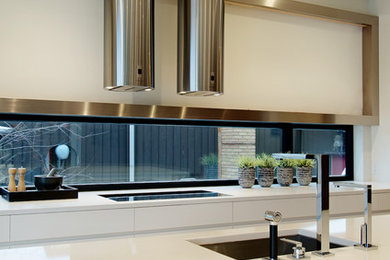 Example of a minimalist light wood floor open concept kitchen design in Calgary with an undermount sink, flat-panel cabinets, white cabinets, quartz countertops and an island