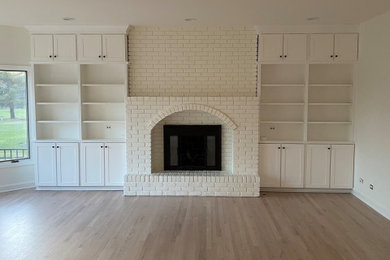 Living room library - large modern enclosed medium tone wood floor, multicolored floor, wood ceiling and wood wall living room library idea in Chicago with white walls, a standard fireplace, a brick fireplace and a wall-mounted tv