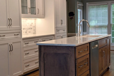 Example of a medium tone wood floor and brown floor kitchen design in Other with a single-bowl sink, shaker cabinets, white cabinets, quartz countertops, white backsplash, marble backsplash, stainless steel appliances, an island and white countertops