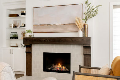 Cette image montre un petit salon craftsman ouvert avec un mur gris, un sol en vinyl, une cheminée standard, un manteau de cheminée en carrelage, un téléviseur dissimulé et un sol marron.