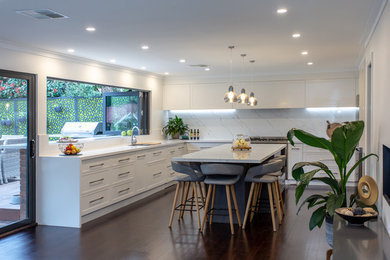 Inspiration for a mid-sized contemporary u-shaped open plan kitchen in Sydney with an undermount sink, shaker cabinets, white cabinets, quartz benchtops, white splashback, marble splashback, stainless steel appliances, dark hardwood floors, with island, brown floor and white benchtop.
