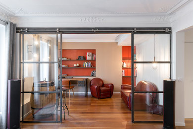 Photo of a mid-sized industrial study room in Paris with orange walls, medium hardwood floors, no fireplace and a freestanding desk.