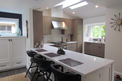 Example of a mid-century modern vaulted ceiling kitchen design in San Francisco with light wood cabinets, white backsplash, cement tile backsplash and white countertops