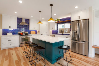 Large transitional l-shaped open concept kitchen photo in Denver with a farmhouse sink, recessed-panel cabinets, white cabinets, blue backsplash, subway tile backsplash, stainless steel appliances and an island