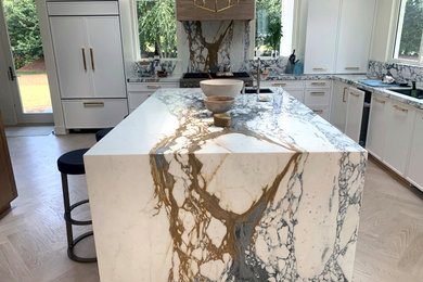 Inspiration for a transitional light wood floor and beige floor eat-in kitchen remodel in New York with an undermount sink, shaker cabinets, white cabinets, marble countertops, multicolored backsplash, paneled appliances, an island and multicolored countertops