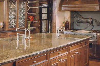 Example of a classic l-shaped kitchen design in Seattle with an undermount sink, raised-panel cabinets, medium tone wood cabinets, granite countertops, black backsplash, stone slab backsplash and stainless steel appliances
