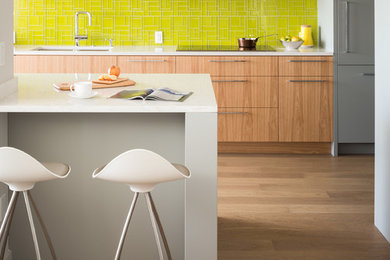 Mid-sized trendy l-shaped medium tone wood floor eat-in kitchen photo in Vancouver with an undermount sink, flat-panel cabinets, medium tone wood cabinets, quartz countertops, green backsplash, glass tile backsplash, paneled appliances and an island