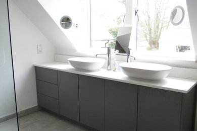 Large modern shower room bathroom in Dorset with flat-panel cabinets, grey cabinets, a walk-in shower, a one-piece toilet, grey tiles, ceramic tiles, white walls, ceramic flooring, a trough sink, solid surface worktops, grey floors and an open shower.