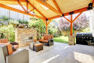 Inspiration for a large backyard stone patio remodel in Other with a fire pit and a roof extension