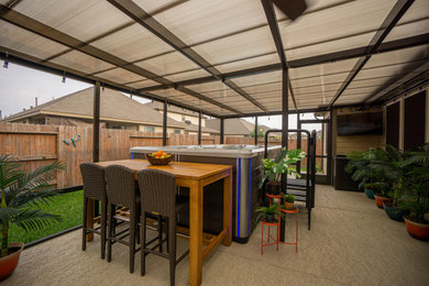 Example of a small island style backyard concrete patio design in Houston with a roof extension