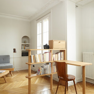 Modern home office and library in Paris with white walls, light hardwood flooring, no fireplace and a built-in desk.