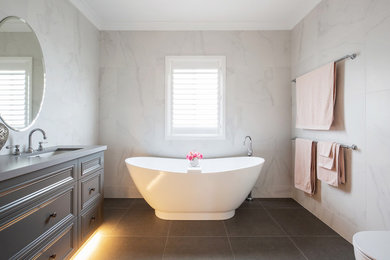 Design ideas for a mid-sized traditional 3/4 bathroom in Sydney with furniture-like cabinets, grey cabinets, a freestanding tub, an open shower, a one-piece toilet, white tile, marble, white walls, porcelain floors, an undermount sink, engineered quartz benchtops, grey floor, a hinged shower door and grey benchtops.