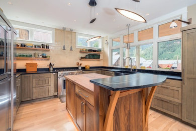 Inspiration for a mid-sized rustic u-shaped light wood floor and beige floor enclosed kitchen remodel in Denver with a farmhouse sink, shaker cabinets, medium tone wood cabinets, soapstone countertops, beige backsplash, subway tile backsplash, stainless steel appliances and an island