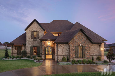 Inspiration for a large timeless brown two-story brick exterior home remodel in Other with a clipped gable roof