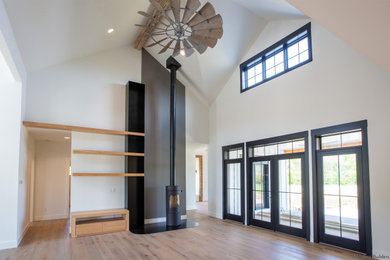 Family room - large farmhouse open concept light wood floor, brown floor, vaulted ceiling and shiplap wall family room idea in Chicago with white walls, a wood stove and a metal fireplace