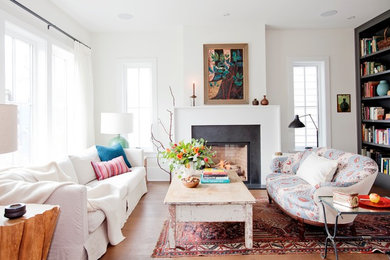Inspiration for a mid-sized transitional enclosed medium tone wood floor and brown floor living room library remodel in Vancouver with white walls, a standard fireplace, a stone fireplace and no tv