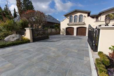 This is an example of a large mediterranean full sun front yard stone driveway in Vancouver.