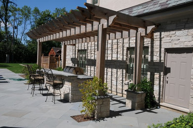 Photo of a mid-sized transitional side yard patio in Chicago with an outdoor kitchen, concrete pavers and a pergola.