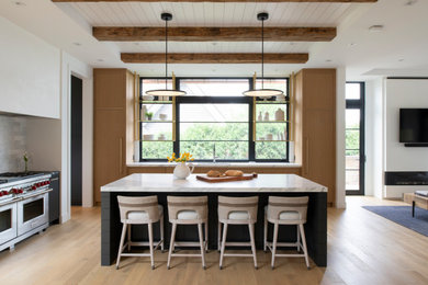 Open concept kitchen - contemporary l-shaped light wood floor, beige floor, exposed beam, shiplap ceiling and tray ceiling open concept kitchen idea in Minneapolis with an undermount sink, flat-panel cabinets, medium tone wood cabinets, stainless steel appliances, an island and white countertops