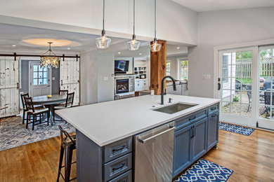 Example of a mid-sized transitional single-wall eat-in kitchen design in DC Metro with flat-panel cabinets, blue cabinets, quartz countertops, blue backsplash, glass sheet backsplash, stainless steel appliances, an island and gray countertops