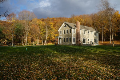 Inspiration for a large farmhouse beige two-story wood house exterior remodel in New York with a clipped gable roof and a shingle roof