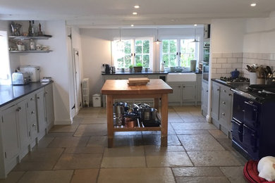 Photo of a large country kitchen/diner in Other with a belfast sink, recessed-panel cabinets, grey cabinets, composite countertops, white splashback, ceramic splashback, ceramic flooring and an island.