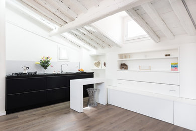This is an example of a small contemporary single-wall open plan kitchen in Rome with a double-bowl sink, flat-panel cabinets, black cabinets, white splashback, panelled appliances and light hardwood floors.