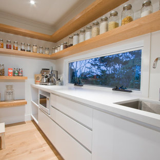 Moderne Küche mit Vorratsschrank, Unterbauwaschbecken, flächenbündigen Schrankfronten, weißen Schränken, Rückwand-Fenster und hellem Holzboden in Brisbane
