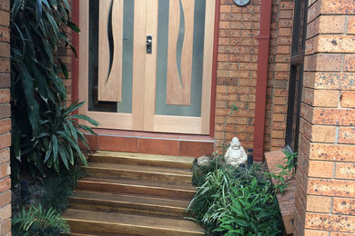 Inspiration for a small contemporary front door in Brisbane with brown walls, ceramic floors, a double front door, a medium wood front door and brown floor.