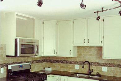 Example of a small classic l-shaped brown floor open concept kitchen design in Kansas City with an undermount sink, recessed-panel cabinets, gray cabinets, stainless steel appliances, an island and beige backsplash