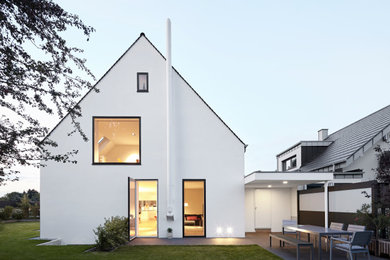 Foto de fachada de casa blanca de tamaño medio de tres plantas con revestimiento de estuco y tejado a dos aguas