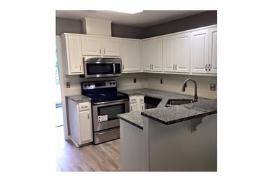 Eat-in kitchen - mid-sized modern u-shaped dark wood floor and brown floor eat-in kitchen idea in Other with a double-bowl sink, raised-panel cabinets, white cabinets, stainless steel appliances, a peninsula and gray countertops
