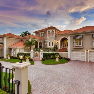 Foto på ett stort medelhavsstil beige hus, med två våningar, stuckatur och valmat tak