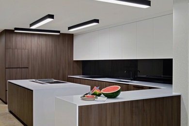 Photo of a mid-sized modern u-shaped eat-in kitchen in Miami with an undermount sink, flat-panel cabinets, white cabinets, quartz benchtops, black splashback, panelled appliances, with island, beige floor and white benchtop.