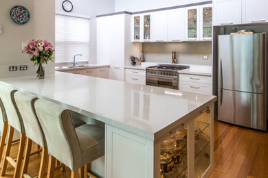 Inspiration for a mid-sized transitional u-shaped eat-in kitchen in Adelaide with recessed-panel cabinets, white cabinets, quartz benchtops, metallic splashback and stainless steel appliances.