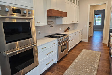 Example of a transitional medium tone wood floor kitchen design in Other with gray backsplash, subway tile backsplash and an island