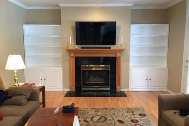 Example of a mid-sized classic enclosed light wood floor and beige floor living room library design in Burlington with beige walls, a standard fireplace, a wood fireplace surround and a wall-mounted tv
