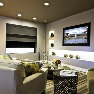This is an example of a large modern enclosed home cinema in Atlanta with grey walls, a wall mounted tv, carpet and green floors.