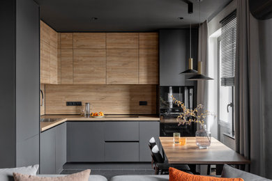 Inspiration for a mid-sized contemporary l-shaped open plan kitchen in Other with a drop-in sink, flat-panel cabinets, black cabinets, wood benchtops, brown splashback, timber splashback, black appliances, ceramic floors, no island, black floor, brown benchtop and wallpaper.